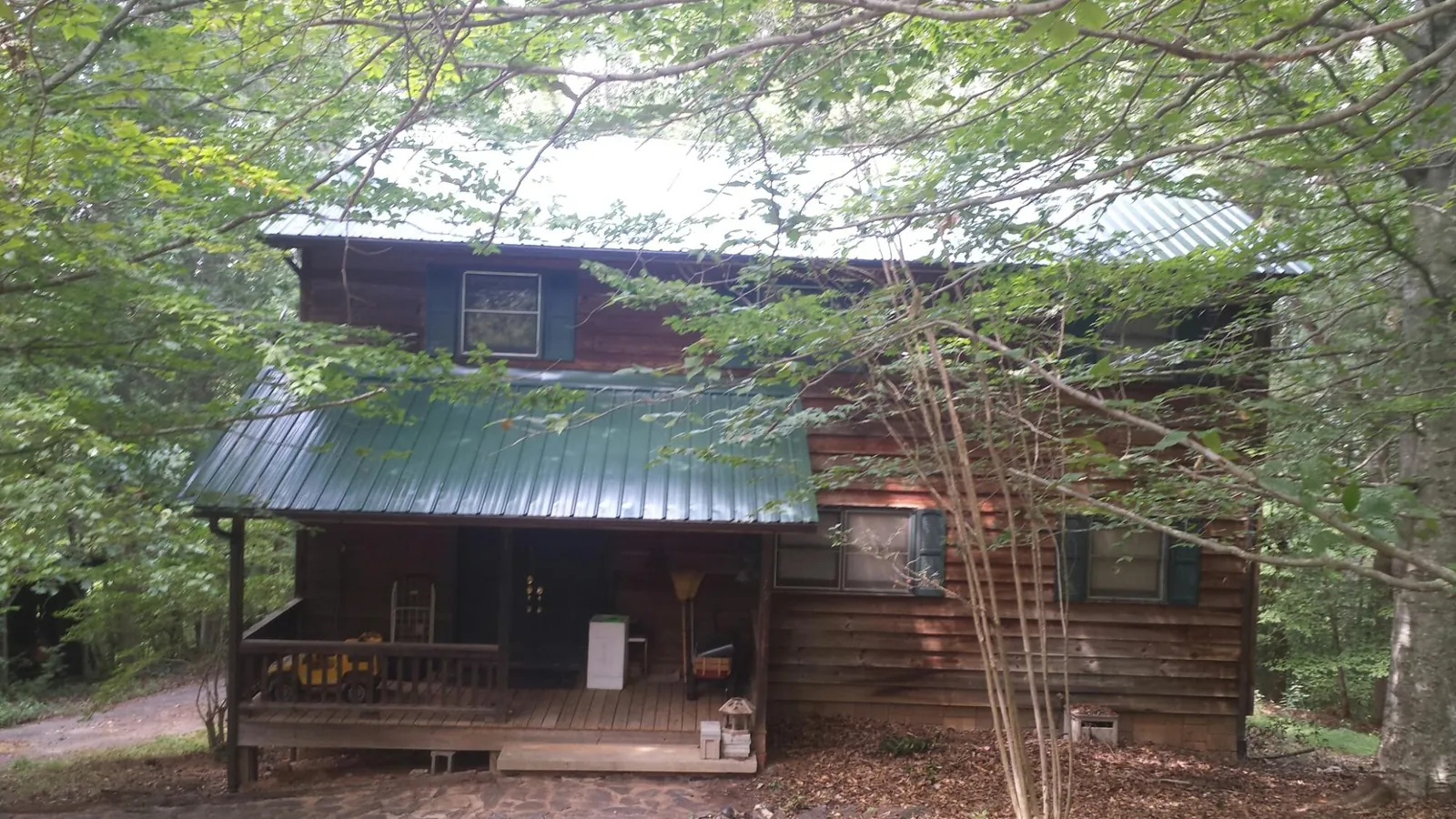 Green metal roof and covered porch on a log cabin in Meansville