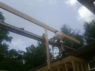 Carpenter setting a ridge beam over a new addition frame — Ice Dam Removal by Roofing Brothers in Meansville