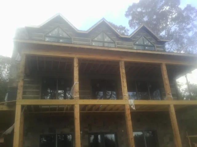 Dormers and porch framing on a large log home under construction — Roof Coating work by our crew in Meansville