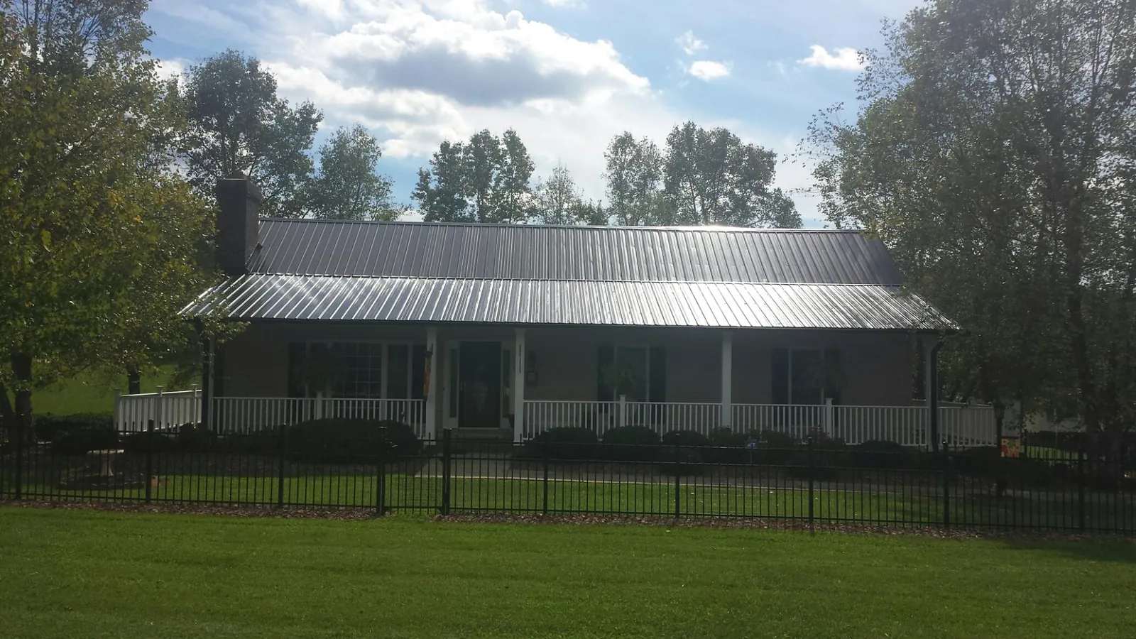 Gray metal roof on a brick ranch with a full width front porch — Gutter Guard Installation work by our crew in Meansville