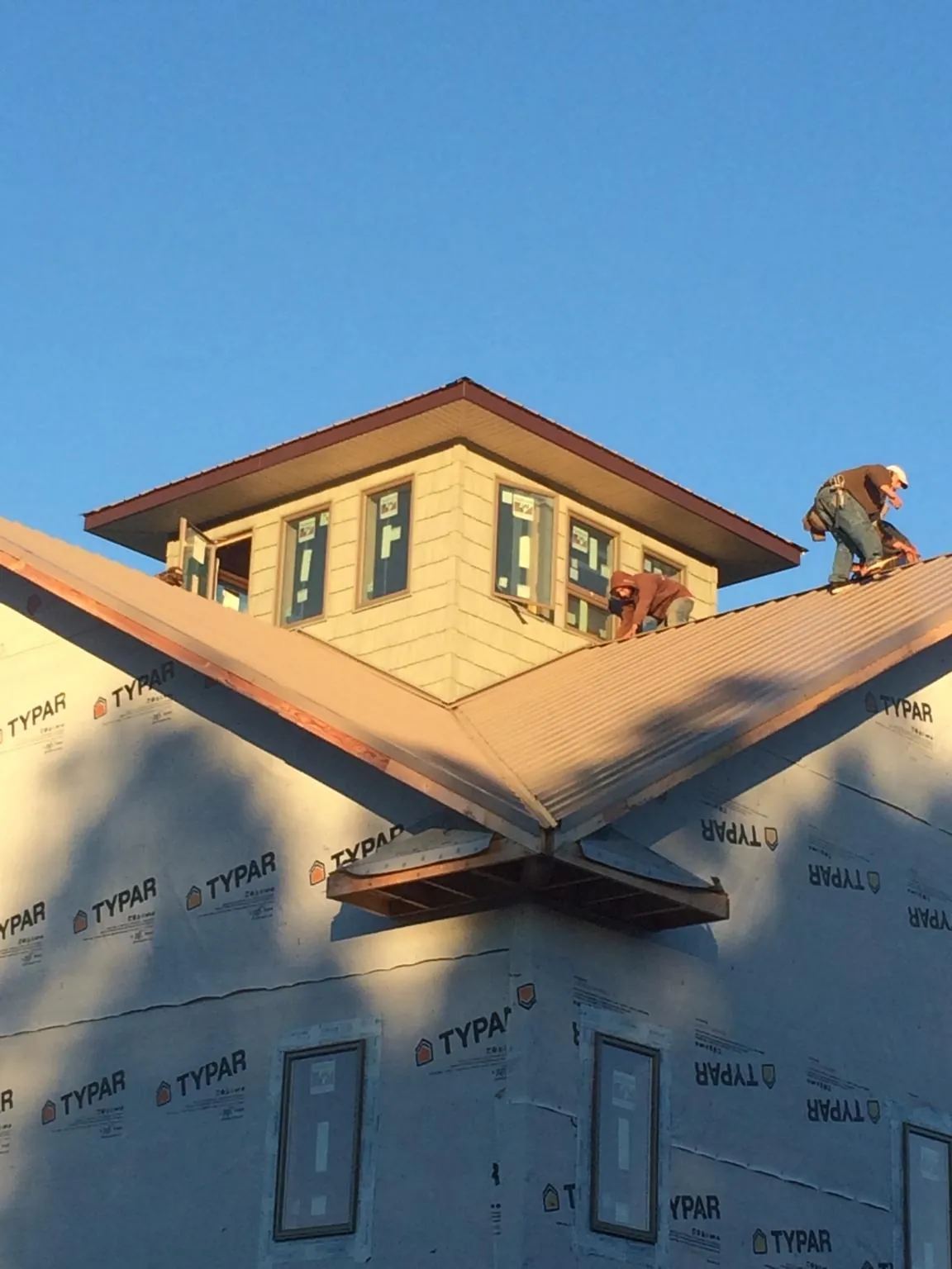 Roofers working around a rooftop cupola on a new metal roof at sunset — Roof Waterproofing in Meansville by Roofing Brothers